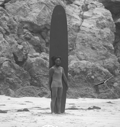 Duke Kahanamoku Stands with Surfboard