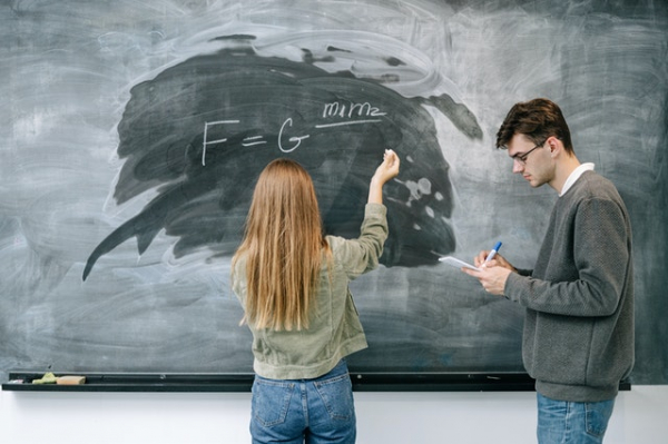 Two people standing in front of chalkboard