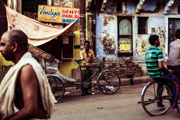 man holding commuter bike in a street in Varanasi, India