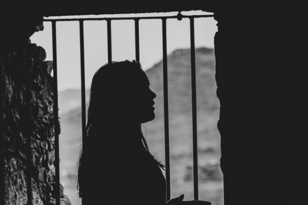 woman female inside prison cell standing beside gates