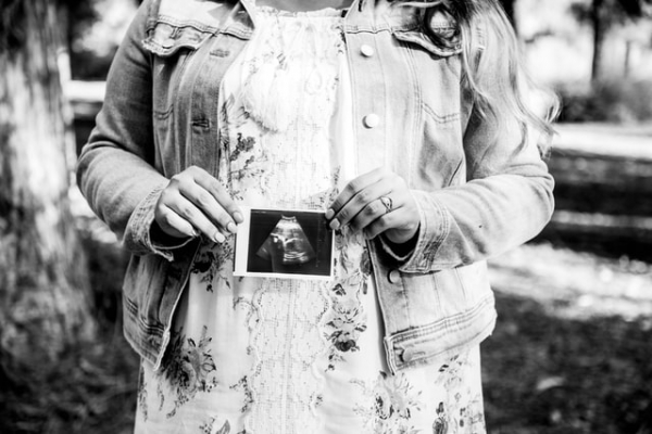 pregnant mom holding small ultrasound photo of her baby