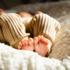 anonymous barefooted baby sleeping on soft bed in sunlight