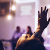 Christian raising hand in worship of God in church