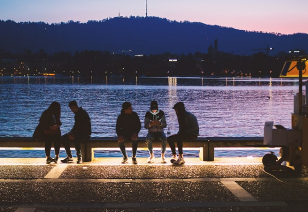 People sitting on a bench beside water