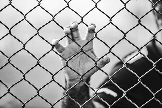 man holding chainlink fence with hand