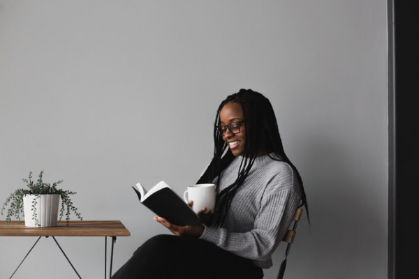 woman reading the Bible happily with a cup in hand