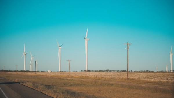 white windmills on a wind farm beside an asphalt road