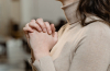 woman praying with her hands clasped