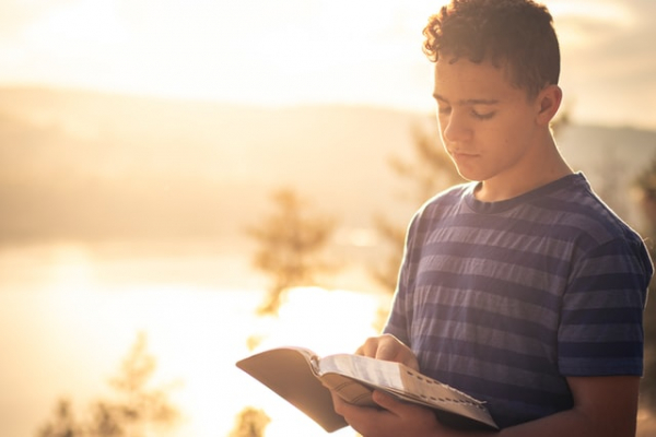 youth reading his Bible outdoors