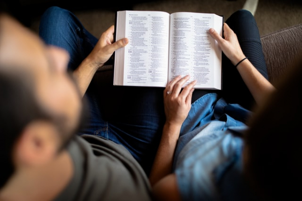 husband and wife married couple reading Bible together