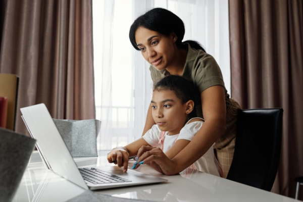 mom helping daughter using laptop computer for home study