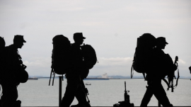 silhouettes of soldiers walking with their gear