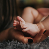 baby's feet held in hand by mom