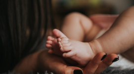 baby&#039;s feet held in hand by mom