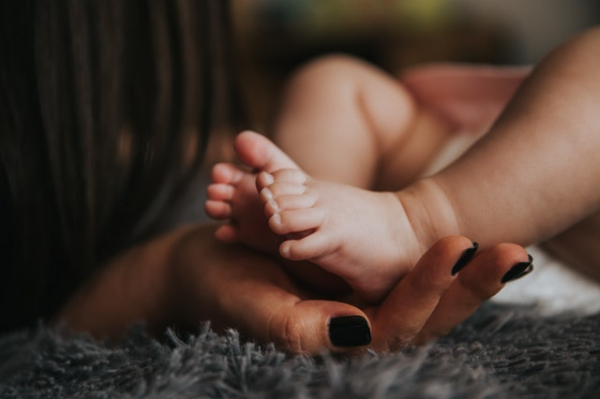 baby's feet held in hand by mom