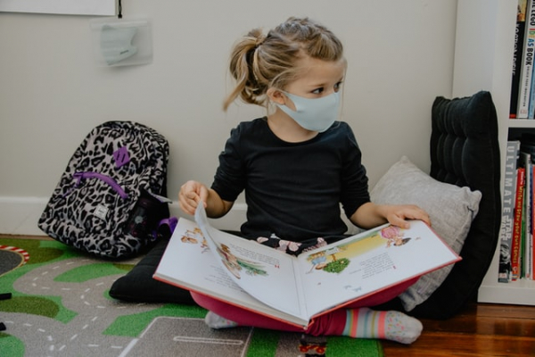 child wearing mask while reading a book at school 