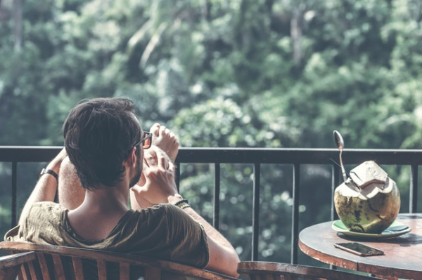 man relaxing on the porch with coconut drink beside him