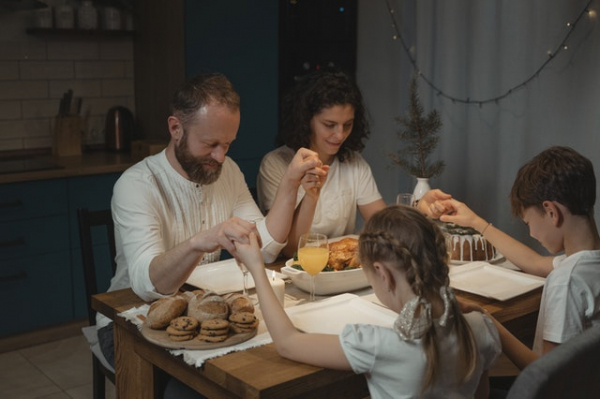 Family praying before eating dinner during Christmas