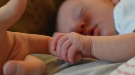 infant holding parent&#039;s finger