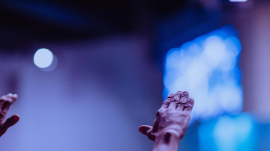 wrinkled hands raised in worship in church