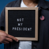 man holding sign saying "not my president"