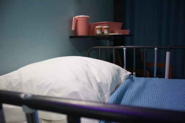 empty hospital bed with medications on the side table